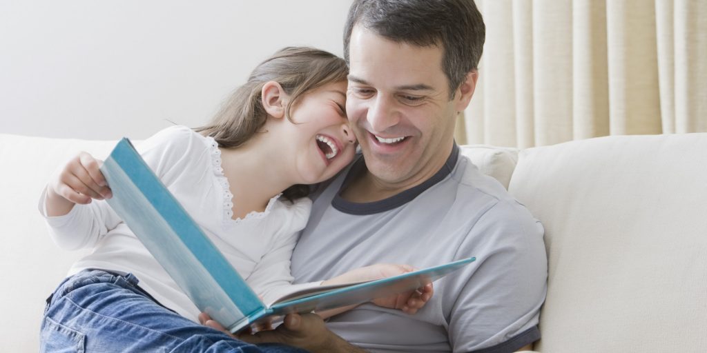 Hispanic father reading book to daughter